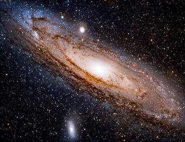 The Andromeda galaxy shown as dark space with stars and a swirling mass or ball of lights at the centre.ba