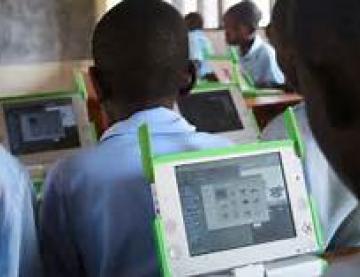 learner looking at a tablet, facing towards class with other learners sat at desks