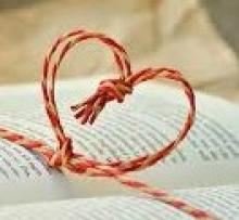 Open book with string in the shape of a heart upright over it.