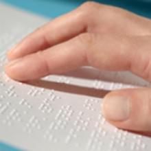embossed braille in close up with a hand touching it