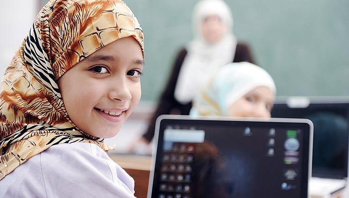 girl of approx 13 years, wearing headscarf, with a tablet in a classroom