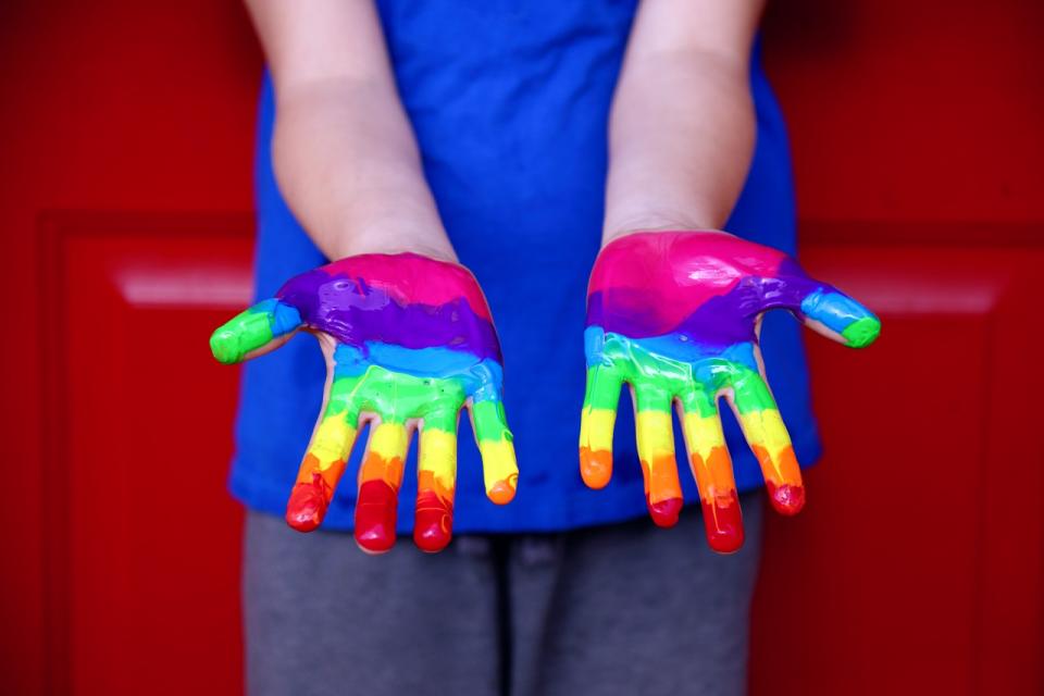 outstretched child's hands with rainbow coloured paint